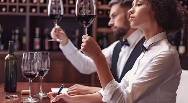 Para degustacji wina: kobieta i mężczyzna oceniają smak wina, notując wrażenia.