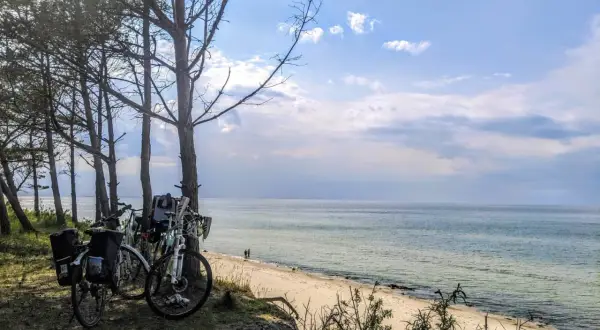 Rowerowe wycieczki to jedne z najlepszych mrzeżyno atrakcje. Rowery zaparkowane przy plaży, morze i niebo.