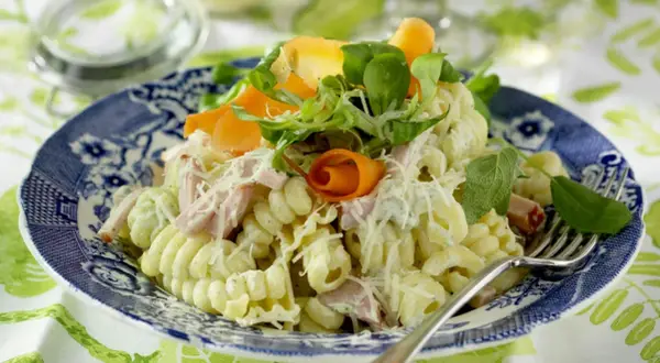 En härlig god pasta sallad med skinka, morötter och örter, toppad med riven ost. Perfekt för en lätt lunch eller middag.