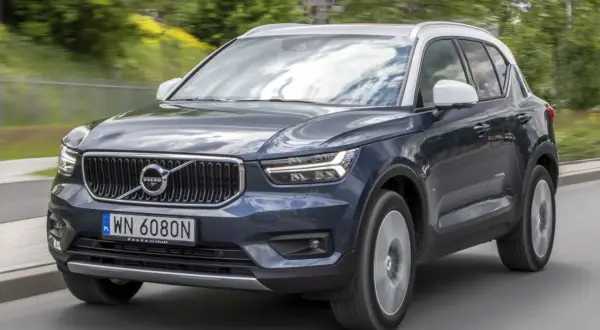 Ciemnogranatowy Volvo XC40 z białym dachem jedzie po drodze. Wiele osób szuka volvo xc40 opinie przed zakupem.