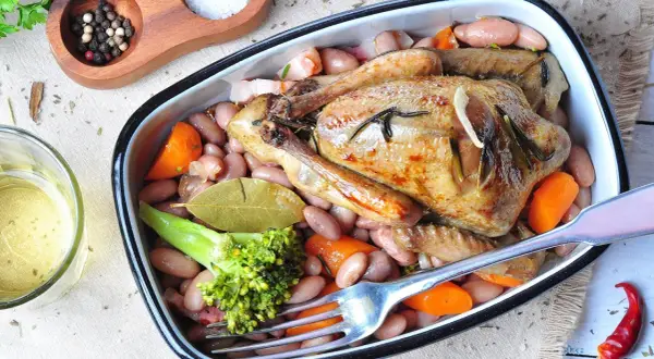 Ein köstlicher Braten von Tauben mit Bohnen, Karotten und Brokkoli, serviert in einer Auflaufform.