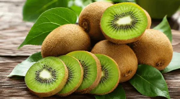 Kiwi frescos, cortados y enteros, sobre madera rústica. Una fuente natural de vitamina K para tu salud.