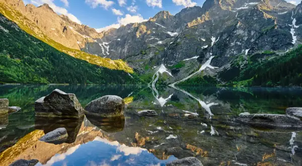 Tatry latem: Morskie Oko odbija skaliste szczyty i zielone zbocza. Idealne miejsce na wakacje, by odkryć bukowina tatrzańska atrakcje.