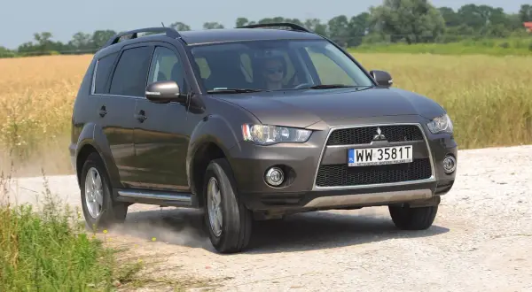 Brązowy Mitsubishi Outlander 2008 na drodze polnej, w tle pole zboża.