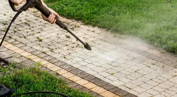 Pulizia del vialetto con idropulitrice per eliminare muschio con candeggina. L'acqua nebulizzata pulisce le fughe tra i blocchi di cemento.