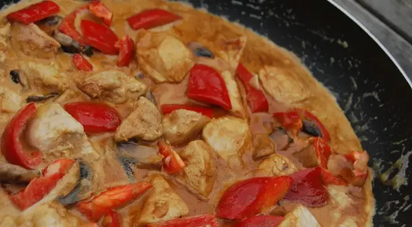 En smakrik chicken karahi i en panna med möra kycklingbitar, röd paprika och champinjoner i en krämig sås.