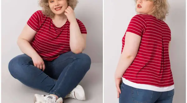 Kobieta plus size w czerwonej bluzce w paski i jeansach siedzi na podłodze.