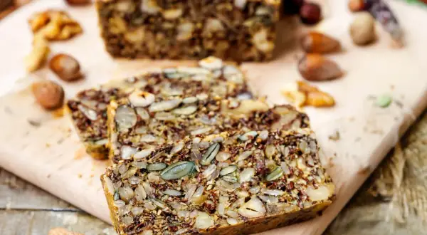 Ein rustikales Keto Brot Rezept mit vielen Kernen und Nüssen, auf einem Holzbrett serviert.