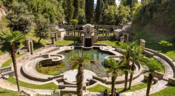 Un incantevole giardino botanico sul Lago di Garda, con un laghetto circondato da architetture in pietra e palme.