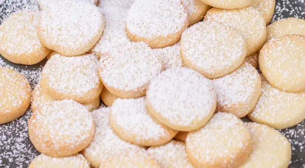 Stos pysznych, okrągłych ciastek niemieckich, oprószonych cukrem pudrem. Idealne na święta!