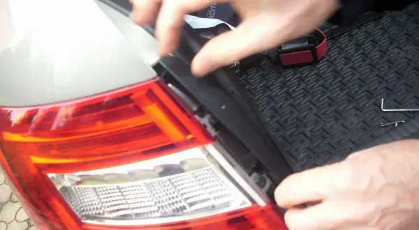 Wymiana żarówki w tyle Seat Ibiza. Dłonie demontują element lampy, przygotowując do wymiany.