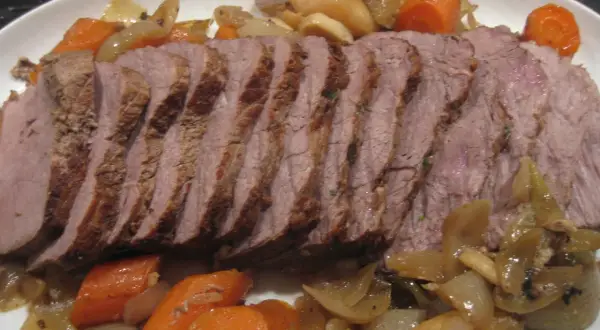 Skivad kalvstek i ugn serverad med rotfrukter och lök. En härlig middag!