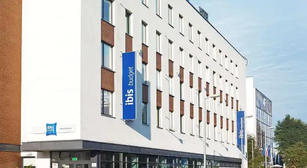 Nowoczesny budynek hotelu ibis budget z niebieskimi banerami.