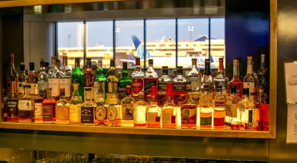Na lotnisku można pić alkohol, co widać po bogatym wyborze butelek z whisky i innych trunków na barze, z widokiem na samoloty.
