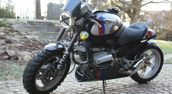 Zmodyfikowany BMW R 1100 R z okrągłym reflektorem i ozdobnymi pasami w barwach narodowych, gotowy na przygodę.