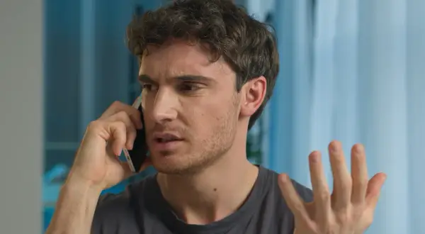 Mężczyzna rozmawia przez telefon, wyrażając frustrację.