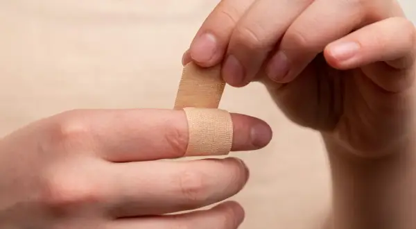 Dłoń zakłada plaster na palec. Czy ziarnina jest niebezpieczna? Pielęgnacja rany jest ważna.