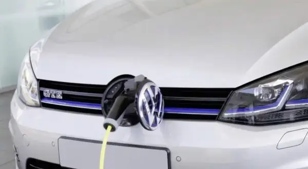 Une Golf 7 GTE blanche est branchée à une borne de recharge. Le câble jaune est visible.