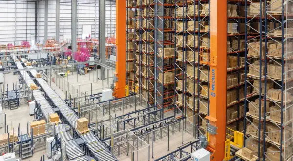 Ein Hochregallager mit automatisierten Förderbändern und einem Regalbediengerät, das für **integrated logistics** optimiert ist.