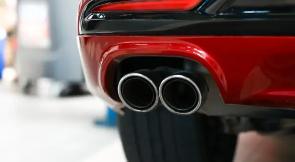 Tylne zderzak czerwonego samochodu z podwójnymi końcówkami wydechu. Zastanawiasz się, jak długo wypala się DPF na postoju?