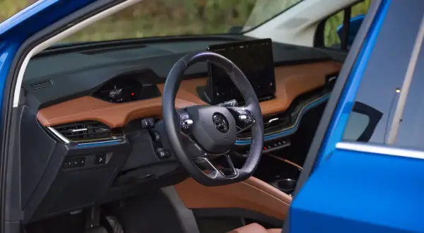 Eleganckie skoda enyaq wnetrze z brązową tapicerką, czarną kierownicą i dużym ekranem multimedialnym.