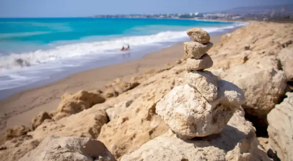 Kamienna wieża na skalistym brzegu, w tle turkusowe morze i piaszczyste plaże Pafos.