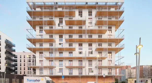 Edificio moderno con balcones de madera y metal. Posiblemente pisos de protección oficial en Barcelona, La Caixa, con vehículos aparcados.