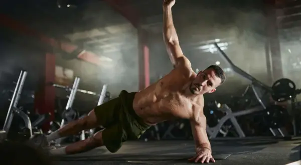 Mann trainiert seine **abs muskeln** in einem Fitnessstudio. Er macht eine seitliche Plank-Übung, wobei sein Körper gerade und angespannt ist.