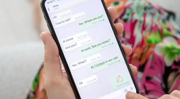 Dłoń trzyma smartfon z otwartym WhatsAppem, pokazującym rozmowę. To może być pomocne, gdy uczysz się, jak założyć WhatsApp krok po kroku.