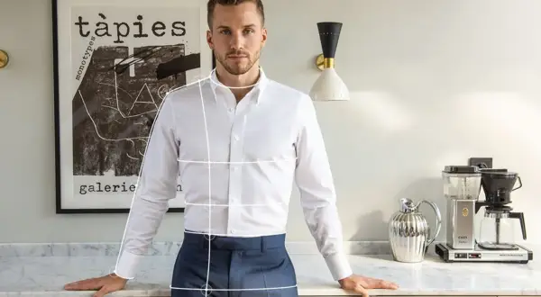 Uomo in camicia bianca e pantaloni blu, con linee bianche sovrapposte che indicano come arrotolare le maniche della camicia.