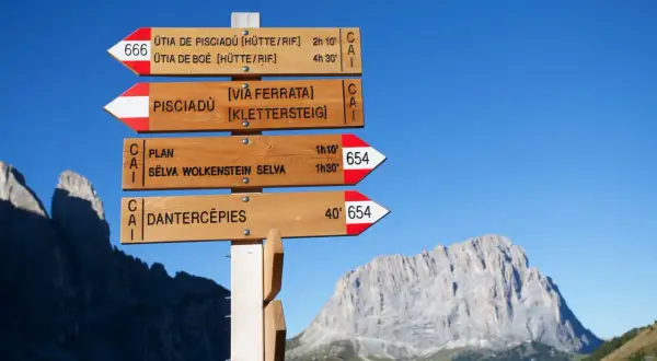 Drewniany drogowskaz w górach we Włoszech wskazuje szlaki na Pisciadù, Dantercepies i inne.