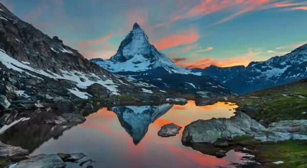 Zachód słońca nad jeziorem z odbiciem Matterhornu. Widok na wejście na Matterhorn, ośnieżone szczyty i malownicze niebo.