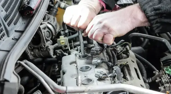Mechanik wymienia świece zapłonowe w silniku. Pamiętaj o regularnej wymianie, by silnik pracował sprawnie.