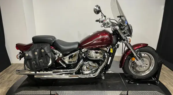 Motocicleta Suzuki Marauder 800 roja con alforjas de cuero y parabrisas.