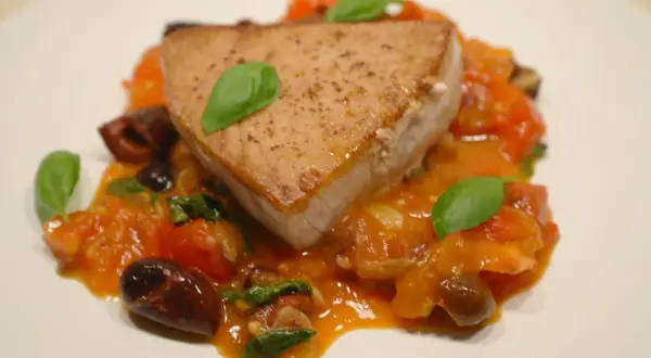En saftig bit tonfisk serveras med en smakrik tomatsås, oliver och färsk basilika. Ett perfekt tonfisk recept för en härlig middag.