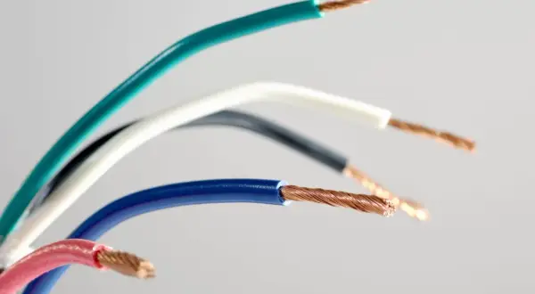 Pięć przewodów elektrycznych w różnych kolorach: zielonym, białym, czarnym, niebieskim i różowym, odsłaniających miedziane żyły. Różnorodność kolorów faz ułatwia identyfikację.