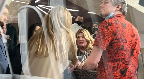 Jakub Łuczak, partner Beaty Kozidrak, w czerwonej koszuli z komiksowym wzorem, rozmawia z kobietą o blond włosach.