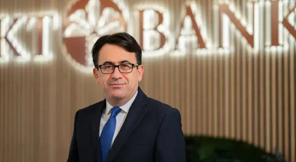 Mann in Anzug vor KT Bank Logo. Positive KT Bank Erfahrung durch professionelles Auftreten.