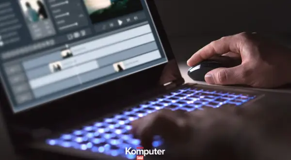 Dłoń steruje myszką przy laptopie z podświetlaną klawiaturą, edytując wideo w formacie HEVC.