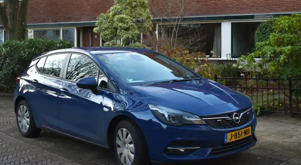 Niebieski Opel Astra K 1.6 CDTI zaparkowany przed domem z cegły.