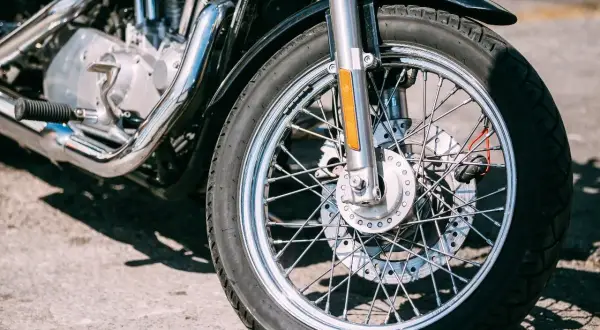 Zbliżenie na przednie koło motocykla z widocznym silnikiem i chromowanymi elementami.