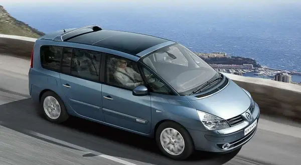 Niebieski Renault Espace 4 z panoramicznym dachem jedzie malowniczą trasą nad morzem.