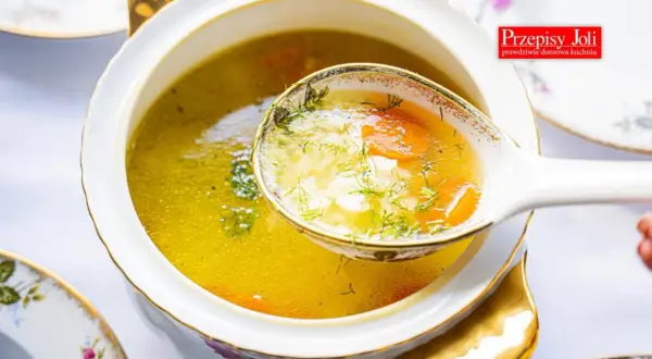 A ladle lifts a spoonful of the **najlepsza zupa ryżowa**, revealing tender rice, carrots, and dill in a golden broth.