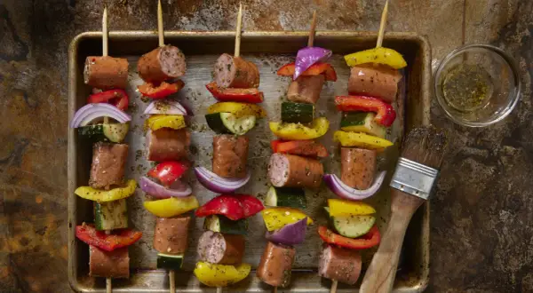 Spiedini di carne succulenti con peperoni, cipolle e zucchine, pronti per essere grigliati.