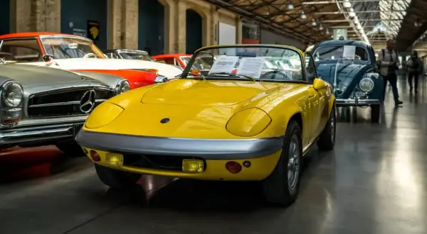 Gelber Lotus Elan Sprint, Baujahr 1972, mit dem Kennzeichen 07. Daneben ein Mercedes-Benz und ein VW Käfer.