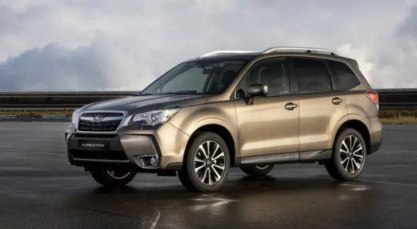 Subaru Forester color bronce, estacionado en asfalto mojado, con nubes en el cielo. A pesar de su apariencia, algunos **subaru forester problemas** son conocidos.
