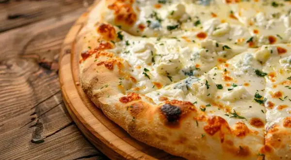 Pyszna pizza z czterema rodzajami sera, posypana ziołami, na drewnianej desce. Idealny ser do pizzy dla smakoszy.