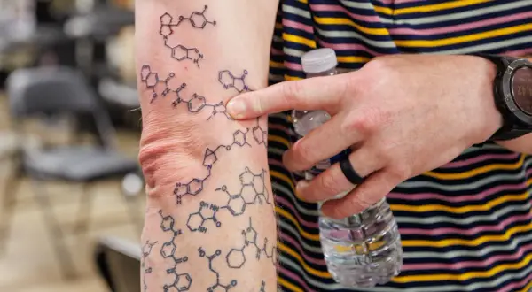 Tatuaż wzór chemiczny na ramieniu, przedstawiający złożone struktury molekularne.