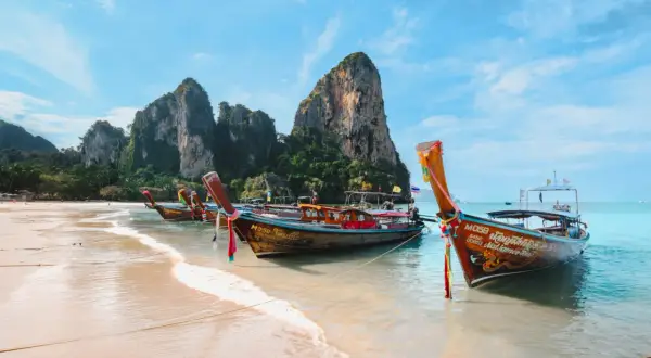 Bateaux traditionnels sur une plage de sable fin, parfaits pour organiser son voyage en Thaïlande et explorer les îles.