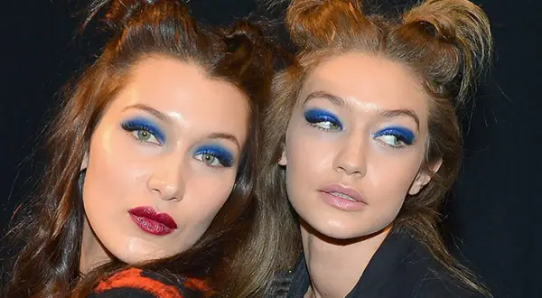 Due modelle con un'audace acconciatura semiraccolto e un vivace trucco occhi blu.